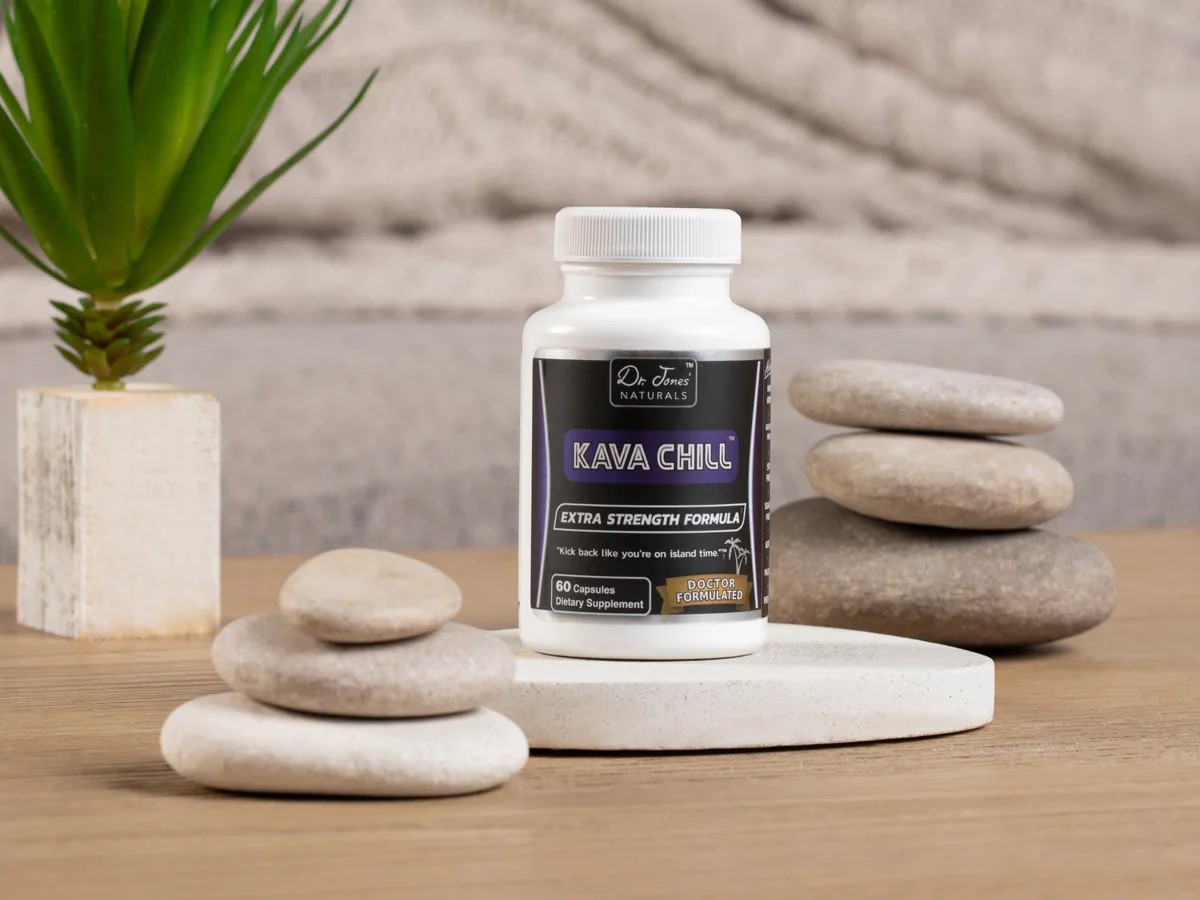 A bottle of Kava Chill on a stone tray beside smooth river stones and a plant