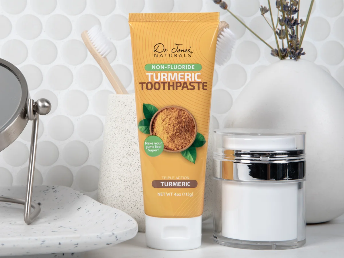 Turmeric Toothpaste on a bathroom counter beside a toothbrush cup and a jar